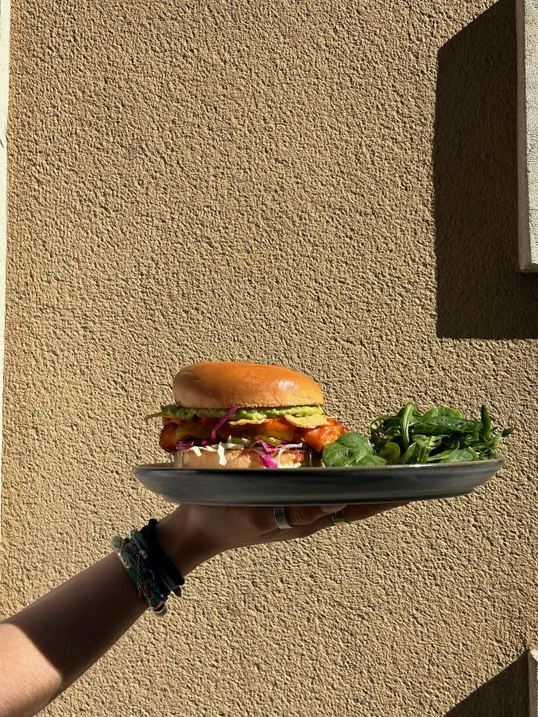 Fried-chicken burger with guacamole and salad, served at lunch