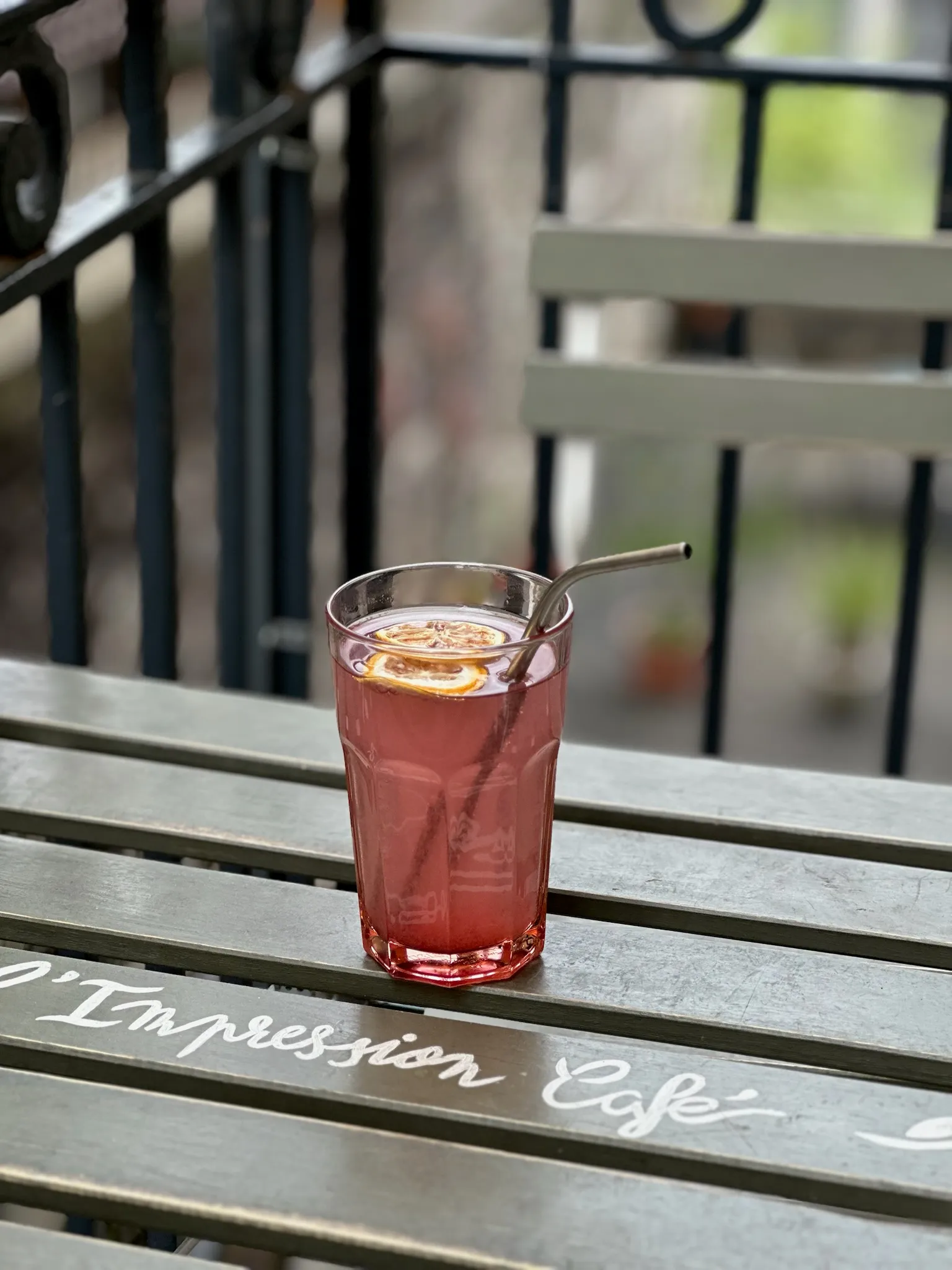 Iced lemonade with a metal straw on a terrace table