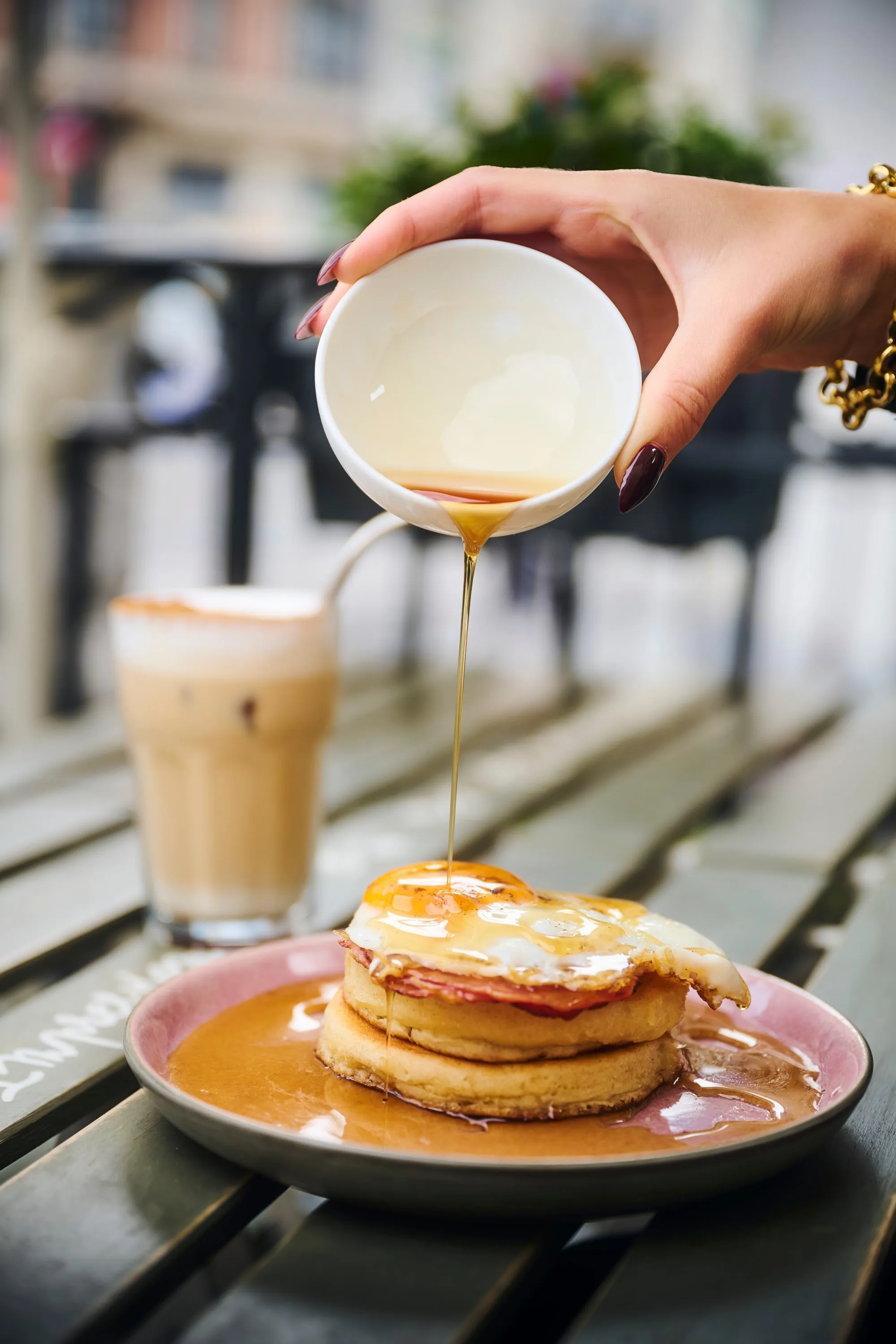 The signature gesture: maple syrup poured over the soufflé-pancake stack, on the terrace.
