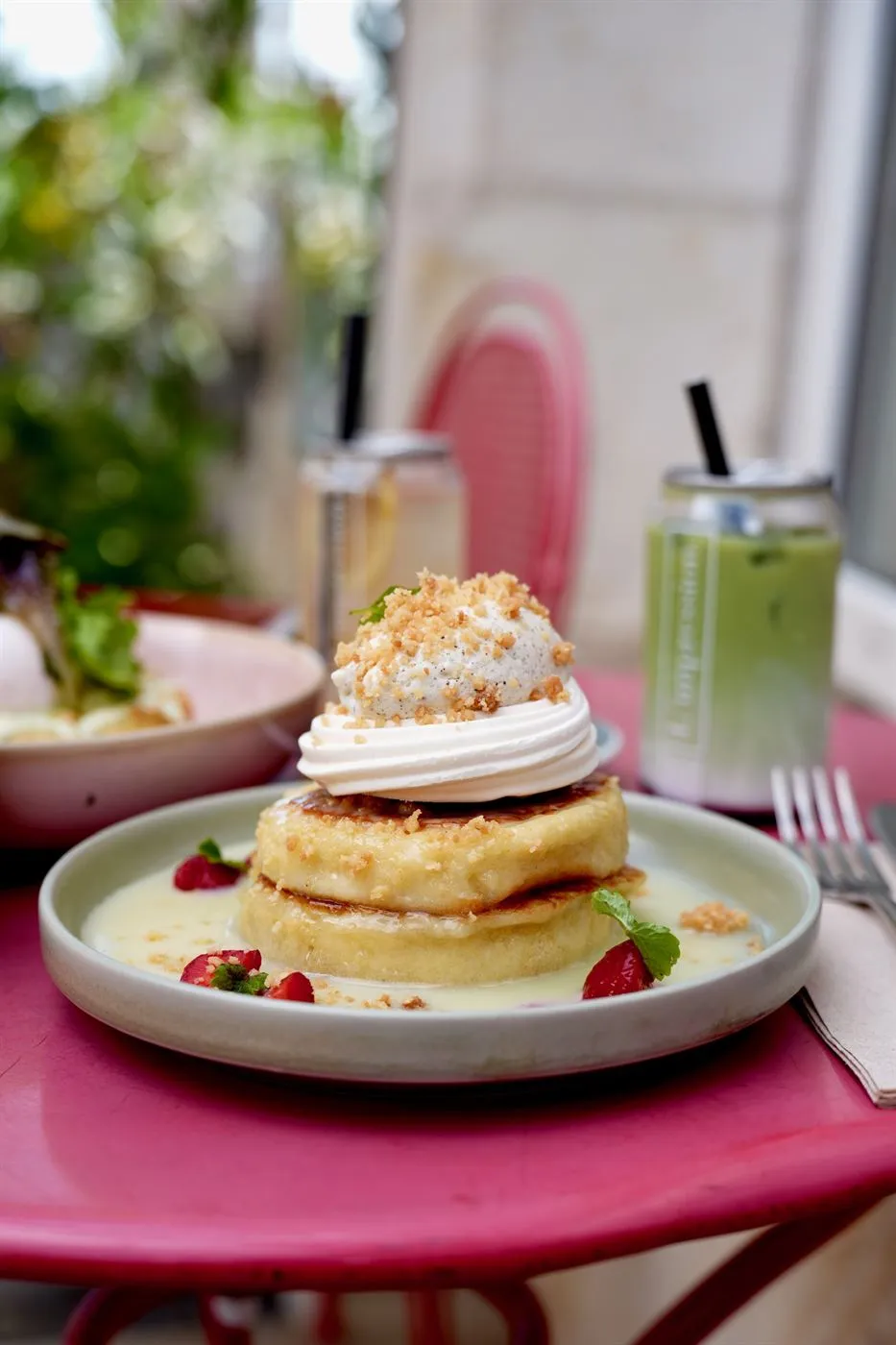 Brunch table set on the sunny terrace with pancakes and iced drinks